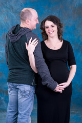 Expecting and excited married couple poses for this studio portrait