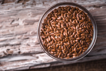 Linen seeds in a glass bowl on wooden stand closeup
