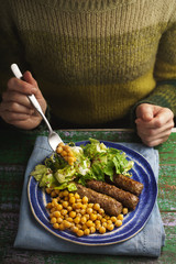 Woman eating chevanchichi, chickpeas, salade at the table