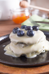 Breakfast, pancakes with maple syrup and fresh berries in a cast iron skillet. Wooden background. Selective focus