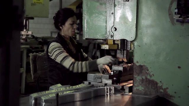 A woman sitting at a machine for forming fasteners