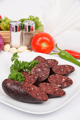 Home blood sausage on a white plate with fennel, parsley and lettuce
