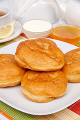 Fried donuts with filling on a white plate with sour cream and jam