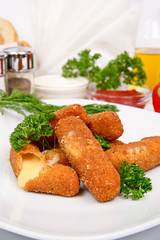 Fried cheese in breadcrumbs with parsley and dill on a white plate