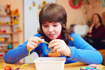 happy kid with disability develops fine motor skills at rehabilitation center for kids with special...