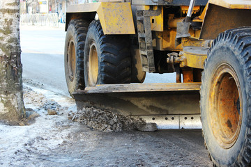 tractor cleans the road in the city of dirty snow