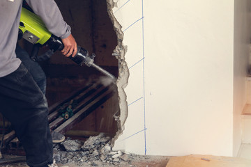 Worker using a jackhammer to drill into wall. professional worker in construction site