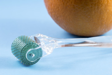 Derma roller for medical micro needling therapy with orange. Tool also known as: Derma roller, mesoroller, meso-roller, mesopen.