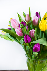 Obraz premium Glass vase with bouquet of beautiful multicolor spring tulips on white background