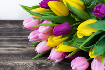 Bouquet of beautiful multicolor spring tulips on white and wooden background