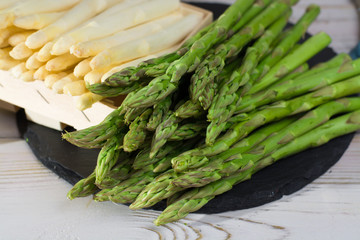 Spring season - fresh white and green asparagus on black stone plate