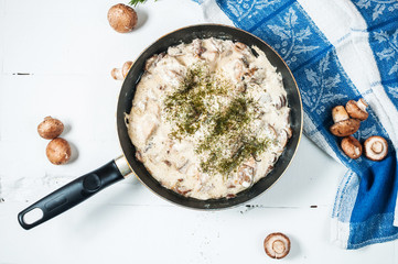 Chicken breast with mushrooms in cream sauce on a pan on the table.
