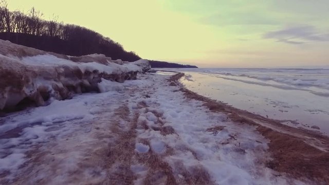 Frozen rock pools on the beach at winter coastal scene. Steadicam footage. Slow motion.
