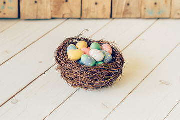 Colorful easter eggs in the nest on wood table background.