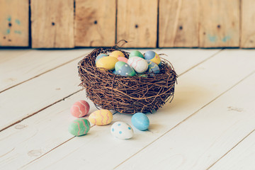 Colorful easter eggs in the nest on wood table background.