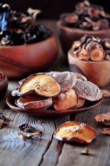 Various organic dried Chinese mushrooms in a wooden bowl on the old wooden background.