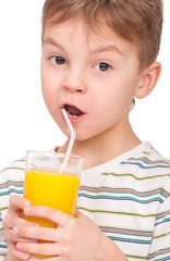 Portrait of happy little boy drinking refreshing orange juice. Smiling child with glass of fresh lemonade.