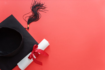 academic hat with diploma on red background