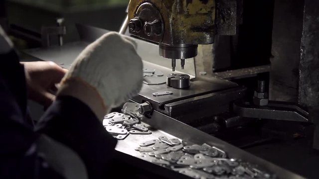 Hands work on a machine for the manufacture small metal fasteners