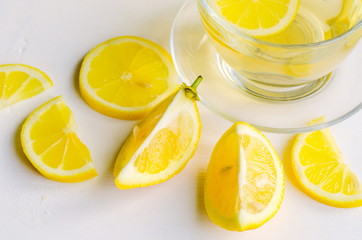 Lemon tea in a transparent cup on white background with slices of lemon