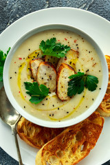 Creamy chicken soup with vegetables in bowl with chiabatta toast, parsley and nigela seeds sprinkle on stone table