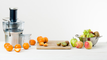 Modern electric juicer and various fruit on kitchen counter, healthy lifestyle concept - obrazy, fototapety, plakaty