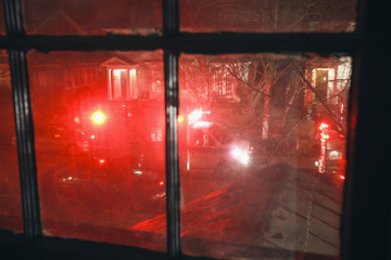 Blurry residential neighborhood emergency scene seen through window.