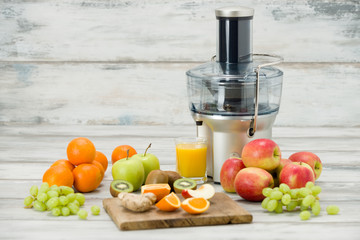 Modern electric juicer, various fruit and glass of freshly made juice, healthy lifestyle concept