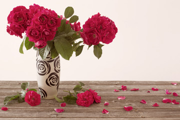 red roses in vase on old wooden table