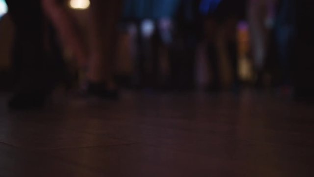 Crowd Of People Dancing On A Dancefloor, Close-up Footage Of People Actively Moving Their Feet To The Music. Dancing Legs With Disco Lights.