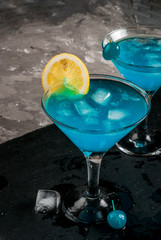 Party, cocktails blue lagoon or blue curacao on a slate tray on concrete stone table copy space