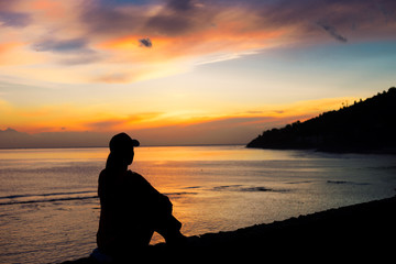 Silhouette of a woman sitting near the ocean