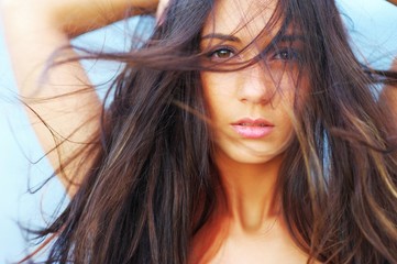 Portrait of a beautiful brunette girl with long hair waving wind