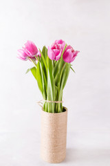 Naklejka na ściany i meble Pink tulips on a light background in handmade Vase. Pink tulip. Tulips. Flowers. Flower background. Flowers photo concept. Holidays photo concept. Copyspace