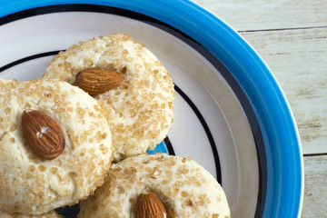 Chinese almond cookies in colored plate on light wood background, top view