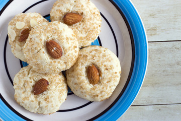 Chinese almond cookies in colored plate on light wood background, top view