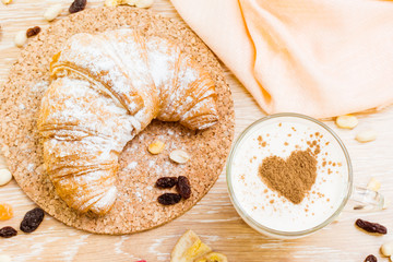 Молочный напиток с молотой корицей и круассан на пробковой подложке