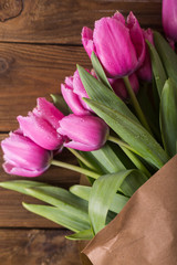 Pink tulips in a package of craft on the wooden background. Pink tulip. Tulips. Flowers. Flower background. Flowers photo concept. Holidays photo concept. Copyspace