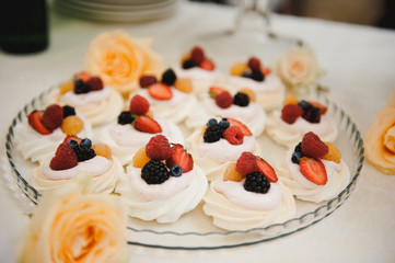 white cupcakes with cream decorated with strawberries and blueberries 