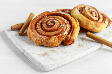 Fototapeta premium Freshly Baked Traditional Sweet Cinnamon Rolls, Swirl on white wooden board