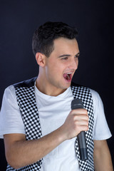 Fototapeta na wymiar Young male black-haired pop singer singing to microphone