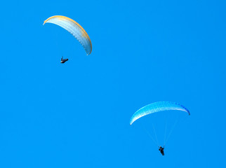 Two paragliders flying in the blue sky. Paragliding. 