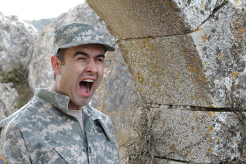 Army soldier screaming in front of some ruins with copy space