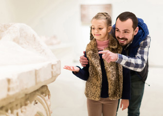 Father and daughter looking at ancient bas-reliefs in museum