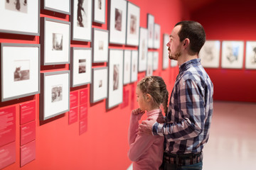 Father and girl exploring exhibition of photos