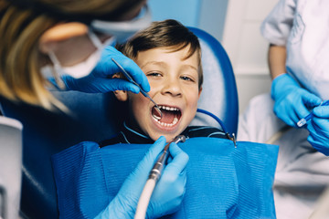 Dentists with a patient during a dental intervention to boy.