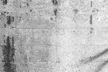 Close-up of a dirty concrete wall with spray paint and smudges in black&white.