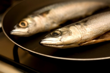 Two ray-finned fish (chub mackerel) in a pan, before frying. Selective focus. 