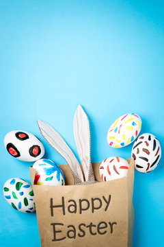 Easter bunny in a paper bag. Blue background. Easter ideas. Easter eggs. Space for text. Black lettering happy easter.