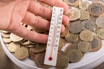 Thermometer in hand beside Turkish Lira coins